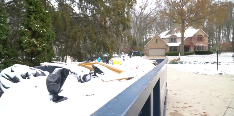 Roll-off dumpster at a property cleanout in winter conditions